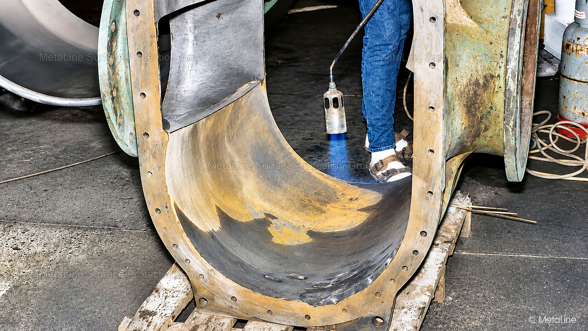 Remise en état de pompes - corps de pompe à piston rotatif usé chez un fabricant de papier d'Allemagne centrale. La pièce est en train d'être séchée à la flamme afin d'éliminer l'humidité des capillaires. La raison pour laquelle le collaborateur porte des sandales et non des chaussures de sécurité reste un mystère ? Il ne s'agit pas seulement de la sécurité de vos installations, mais aussi de celle de vos collaborateurs